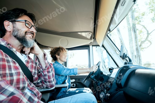 Preview: Woman driver driving a camper van with happy man on passenger seat. Alternative couple enjoying