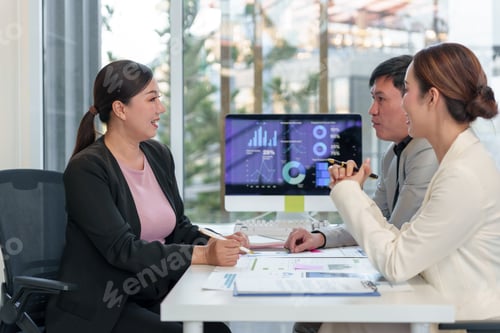 Preview: Business team analyzing financial data on computer and documents in office meeting