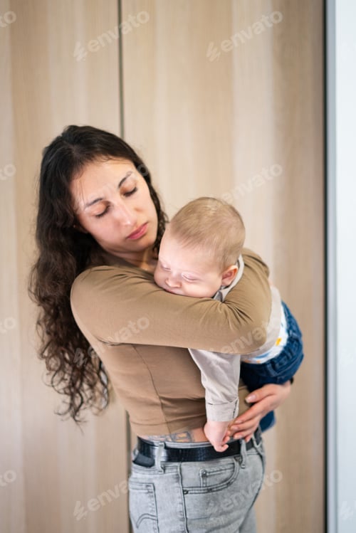 Preview: Latin Mother gently holding sleeping baby at home