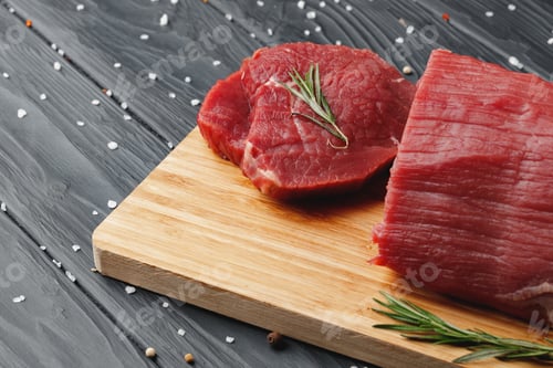 Preview: Beef tenderloin on wooden board on wooden table