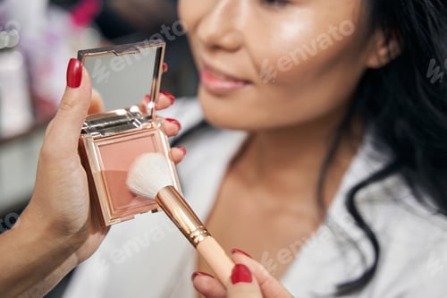 Preview: Focused image of powder brush and toner in female hands