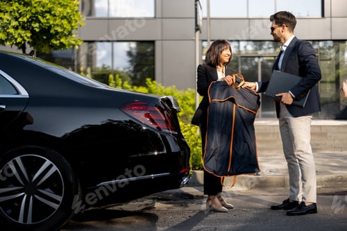 Preview: Female chauffeur gives a businessman his suit, after a business trip by car