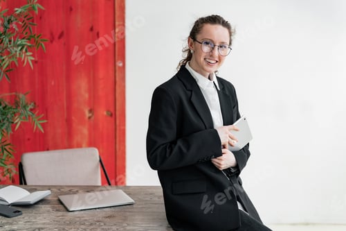 Preview: Engaged businesswoman with tablet, standing confidently in a vibrant workspace.