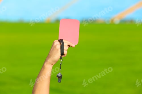 Preview: Football referee holding red card and whistle at stadium, closeup