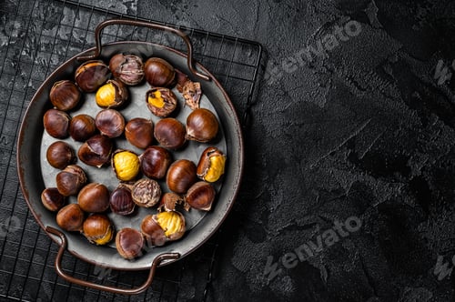 Preview: Cracked roast chestnuts served in a tray. Black background. Top view. Copy space