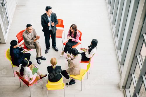 Preview: Top view captures a diverse group in a busy office, collaborating and engaged in discussions. A