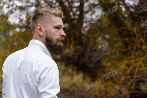 Preview: Young bearded man in white shirt walks on yellow autumn day in park. Spending