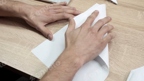 Preview: Close-up of man folding origami paper. Stock footage. Men's hands are folded from white paper