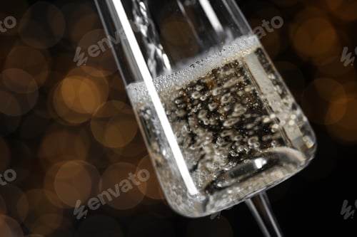 Preview: Pouring champagne into glass against blurred lights, closeup