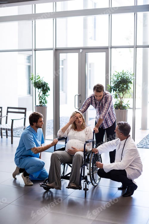 Preview: Male doctor talking to pregnant woman in wheelchair