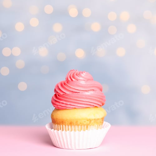Preview: Tasty birthday cupcake with cream on table against festive lights