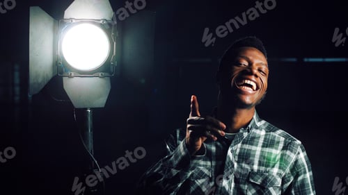 Preview: Young African-American Man In Darkness Coming Close To Camera, Then Studio Light Stand Is Being