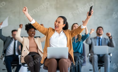 Preview: Happy businesspeople laughing while collaborating on a new project in an office.