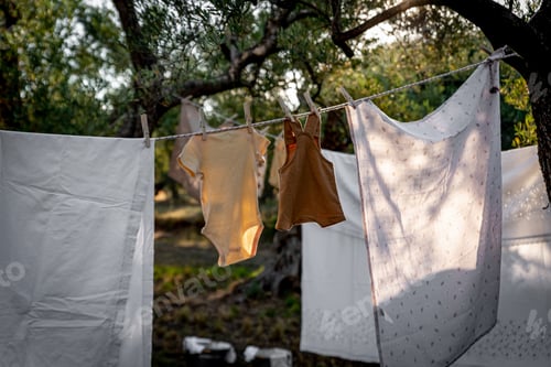 Preview: Baby clothes on clothesline drying in garden. Newborn childhood concept