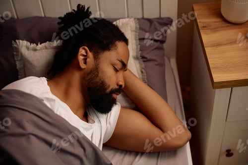 Preview: African American man sleeping in his bed at home.
