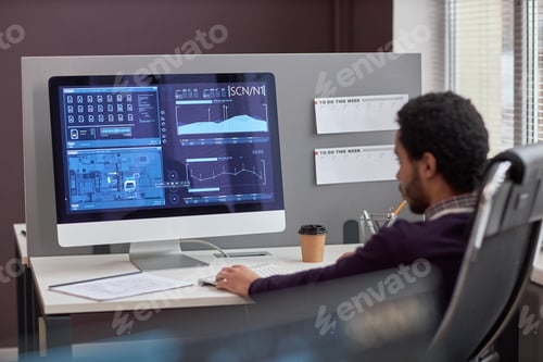 Preview: Back view at male IT engineer working with data on computer screen at workplace, copy space