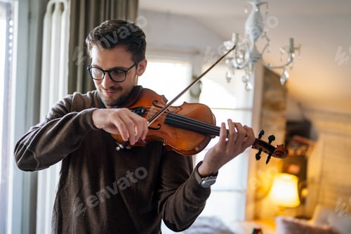 Preview: Young caucasian man playing violin at home. Hobby quality time happiness concept.