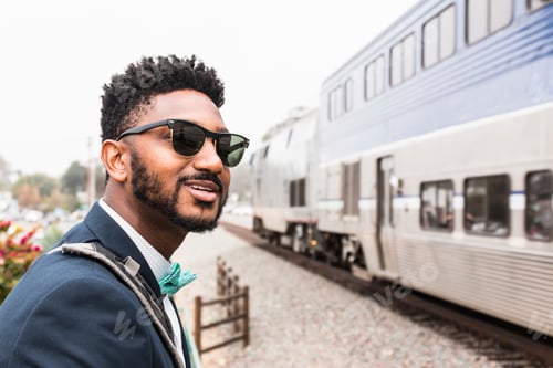 Preview: Young businessman in bow tie watching train arrive at platform