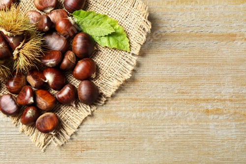 Preview: Fresh sweet edible chestnuts on wooden table, flat lay. Space for text