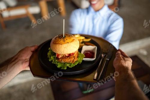 Preview: Waiter serves a fresh burger and fries in stylish restaurant, capturing the essence of great service