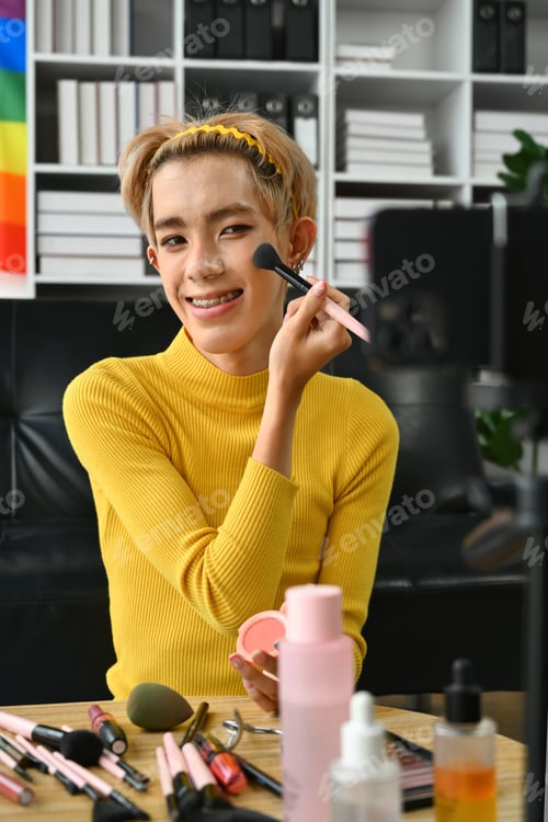 Preview: Smiling Asian gay man blogger filming daily makeup routine tutorial on smartphone.