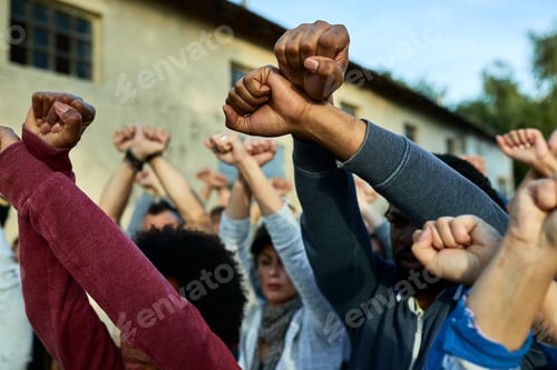Preview: Close-up of crowd of people with clenched fists above head protesting on the streets.