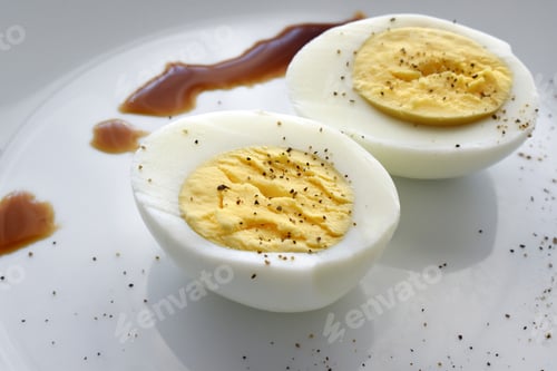 Preview: Boiled egg with black pepper and soy sauce in white plate.