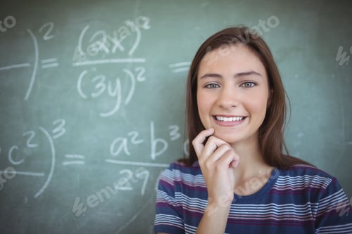 Preview: Teenage girl student standing in classroom, with large chalkboard of math formulas, copy space