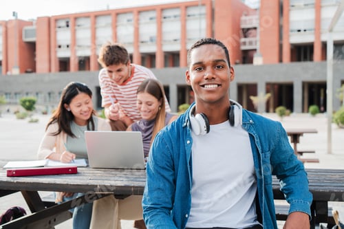 Preview: Young african american male student, smiling and looking at camera sitting with her classmates at