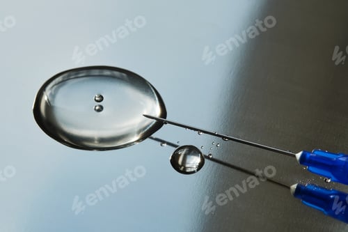 Preview: A drop of medicine flowing from a syringe with a needle.