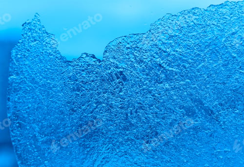 Preview: Piece of ice on glass background. Close-up natural blue texture.