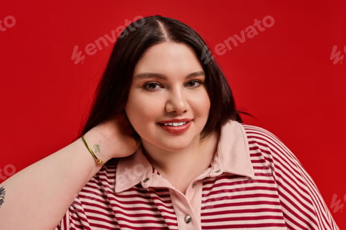 Preview: Stylish plus size woman showcasing confidence against a vibrant red backdrop with charm
