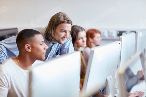 Preview: Male lecturer showing student using computer in higher education college computer room