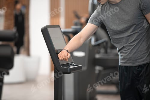 Preview: Man Using Modern Fitness Machine at the Gym
