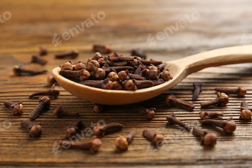 Preview: Aromatic dry cloves and spoon on wooden table, closeup