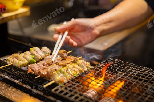 Vista previa: Vendor preparing meat on barbecue grill in Japan