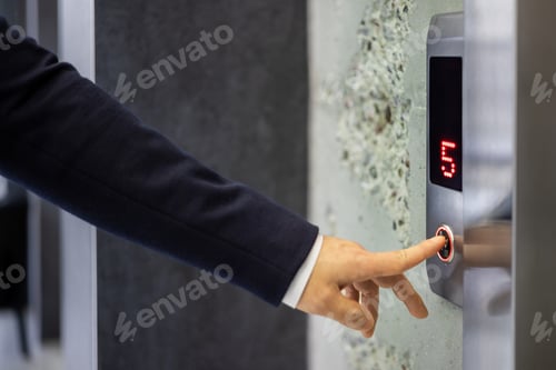 Preview: Businessman pressing an elevator button in modern building