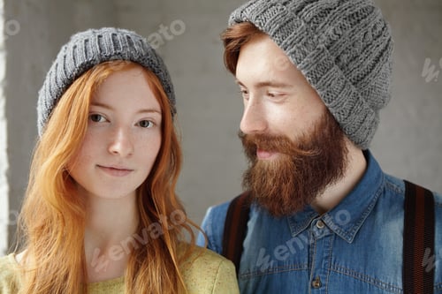 Preview: Studio shot of two attractive friends wearing gray hats indoors. Happy handsome man with stylish bea