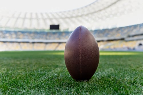 Preview: rugby ball on green grass at stadium with copy space