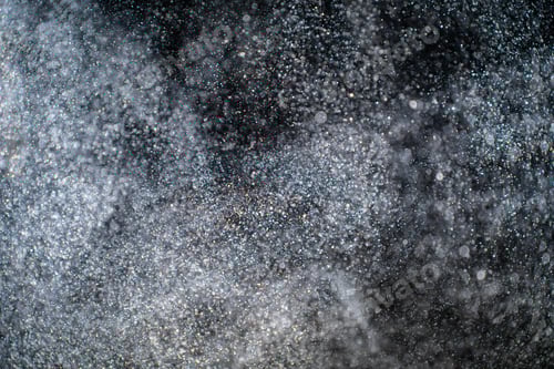 Preview: Dust particles cloud generating abstract shape on black background with copy space for text.
