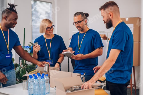 Preview: Diverse volunteers working in a charity donation center and packing clothes and food