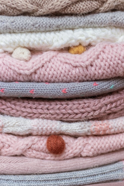 Preview: A stack of knitted baby hats and snoods in beige and pink shades