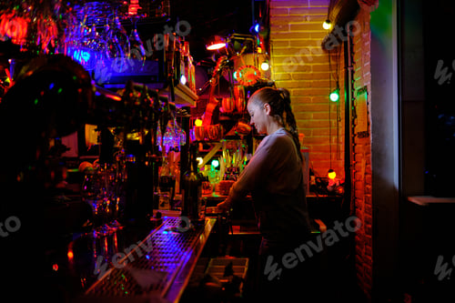 Preview: Female bartender standing behind the counter preparing an order for a customer while working