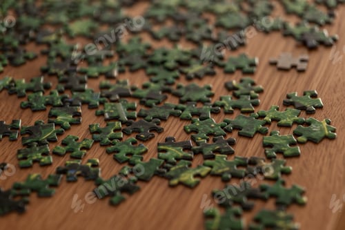 Preview: Scattered green jigsaw puzzle pieces on wooden table