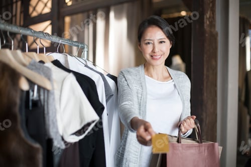 Preview: Mature woman with credit card in clothing store