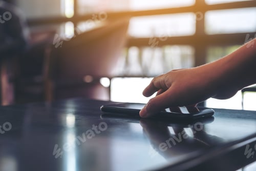 Preview: A hand grabbing and picking up mobile phone on the table