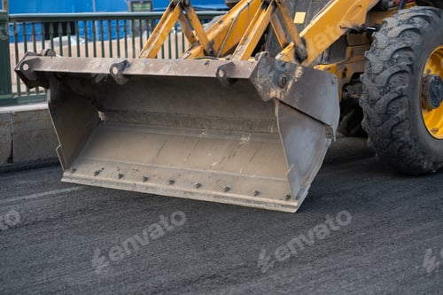 Preview: Repairing motor road with excavator with empty bucket driving on ground prepared for asphalt laying