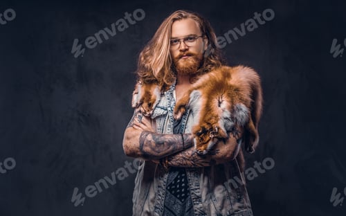 Preview: Portrait of a tattooed redhead hipster male holds a keeps the scarecrow of an owl in a studio