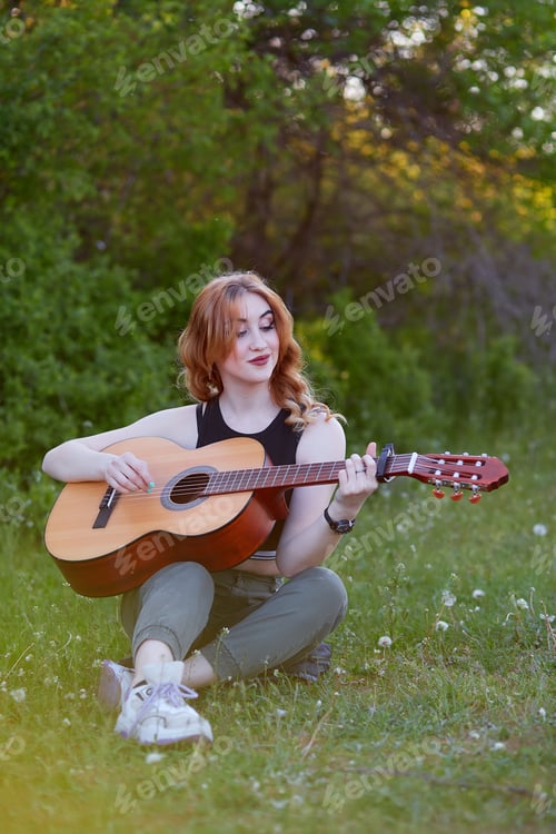 Preview: Smiling woman playing guitar around spring nature. Self-care and mental health cottagecore concept