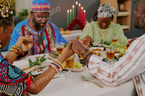 Preview: Black Family Holding Hands and Praying during Kwanzaa Celebration Dinner